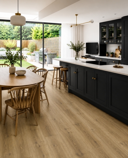 Fellside Oak XL luxury click vinyl flooring in a modern open-plan kitchen with navy shaker cabinets, oak dining furniture and large patio doors, showcasing warm natural oak tones, realistic wood grain and extra-long wide plank design.