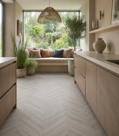 Gran Canaria Herringbone Luxury Click Vinyl Flooring in a modern open-plan kitchen, showcasing light grey oak-effect herringbone vinyl flooring with realistic wood grain detail and natural stone-inspired tones. Waterproof click vinyl flooring installed throughout a contemporary kitchen diner with large windows, modern cabinetry and garden views, highlighting durable wood-look flooring for busy family homes.