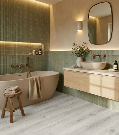 Kirkstone Grey Oak Luxury Click Vinyl Flooring 5mm in a modern bathroom, featuring light grey wood-effect planks, sage green wall tiles, a freestanding bath and contemporary floating vanity.
