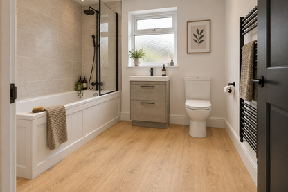 A modern bathroom interior with a white bathtub, black-framed glass shower screen, light wood floor, white vanity with sink, toilet, framed wall art, and a black heated towel rail.