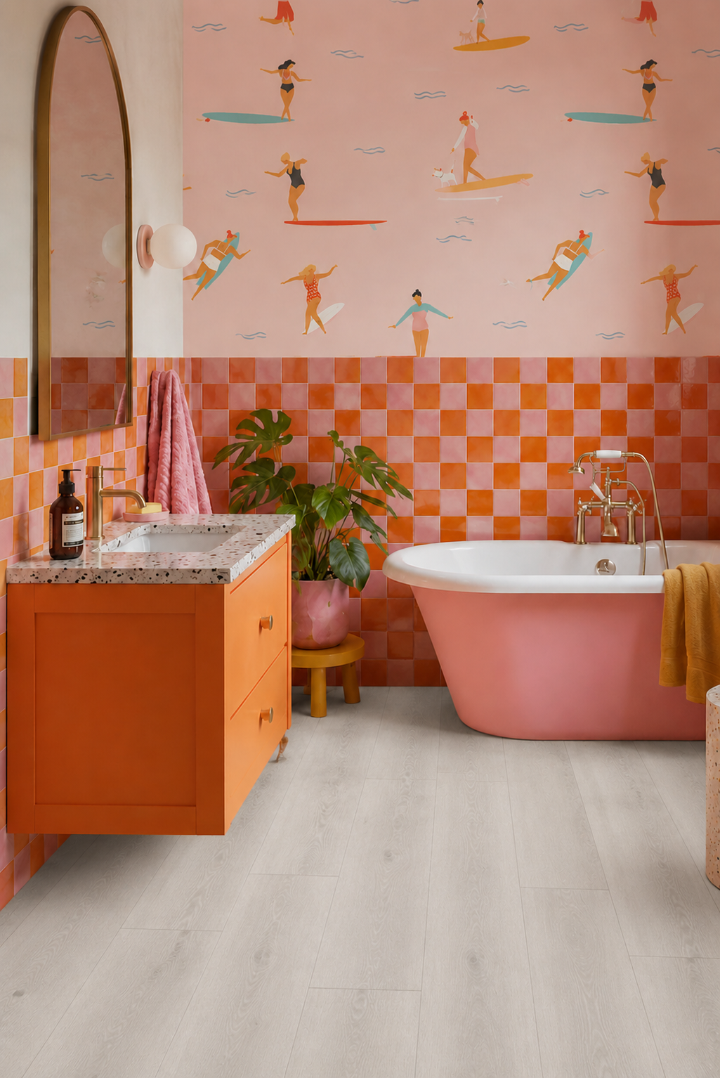 Pewter Grey Oak SPC flooring in a modern bathroom with realistic light grey oak wood grain planks, waterproof luxury vinyl flooring, pink and orange bathroom décor, freestanding bathtub, terrazzo vanity top and contemporary interior styling.