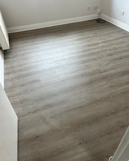Light gray wood-look laminate or vinyl plank flooring installed in a room with white walls and baseboards.