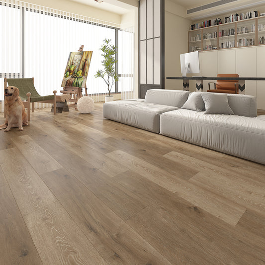 Modern open-plan living space with warm natural oak luxury vinyl plank flooring, featuring wide wood-effect boards with realistic grain and knot detailing. The bright, contemporary interior includes a low white sofa, home office, floor-to-ceiling windows, shelving, an artist's easel, indoor plant and a dog, showcasing the flooring's natural warmth and seamless finish.
